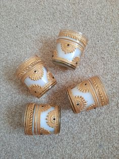 four gold and white vases sitting on the floor in front of a beige carpet