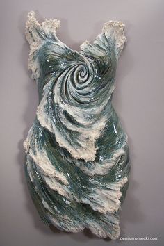 a sculpture made out of clay with white and green swirls on the top, against a gray background