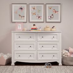 a baby's room with two pictures on the wall and a dresser in front of it