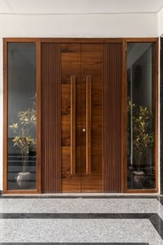 the front door is made of wood and has glass panels on each side, along with two planters