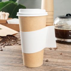 a cup of coffee sitting on top of a wooden table next to a paper towel