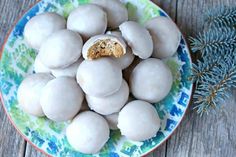 a plate filled with white chocolate covered donuts next to a sprig of rosemary