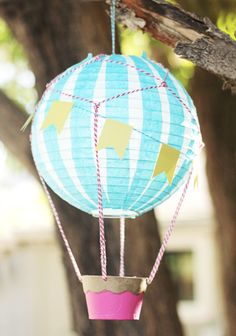 a blue and pink hot air balloon hanging from a tree