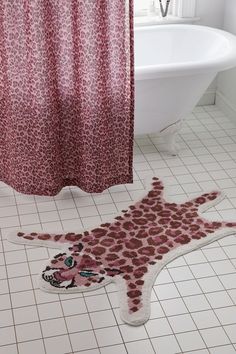 a bathroom with a bathtub, shower curtain and animal rug on the floor in front of it