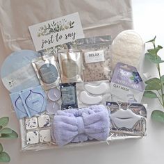 an assortment of items in a gift bag on a table with green leaves and flowers