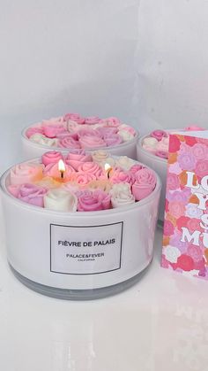 two pink roses in a white container with a card next to it on a table