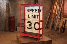 a speed limit sign sitting on top of a wooden platform in a room filled with wood planks