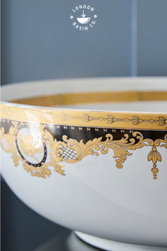 a large white bowl with gold trimmings on the bottom and sides, sitting on a table