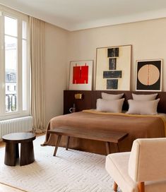 a bed sitting in a bedroom next to a window filled with lots of light brown furniture