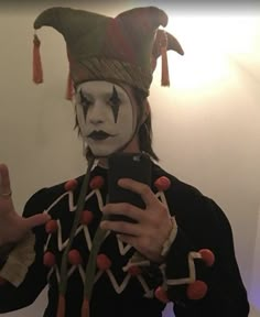 a man dressed as a clown taking a selfie in front of a mirror with his cell phone