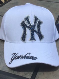 Check out these Ahhhhh-mazing Yankees hatsembellished with 100% authentic Swarovski crystal rhinestones These hats are a classic style ladies cut/fit, and have an adjustable velcro strap across the back. Choice of white or any colored hat. The white hat has navy blue stones with clear outline and the Yankees on the brim. The navy hat is made with all clear crystal and Yankees on the side of the hat I custom make these hats, and I can make them in just about any style or color combo. Please feel Adjustable Rhinestone Baseball Cap With Curved Brim, Rhinestone Baseball Cap One Size, Rhinestone Embellished One Size Baseball Cap, White Hats With Rhinestones And Curved Brim, Adjustable Baseball Cap With Bling, White Rhinestone Hat With Curved Brim, Adjustable Rhinestone Cap, Decorative Hats, Rhinestone Baseball Cap