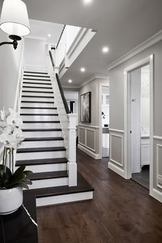 a white and black staircase with flowers in a vase on the bottom floor next to it