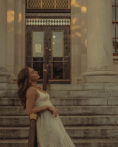 a woman in a white dress sitting on some steps