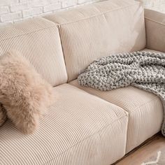 a couch with a blanket on top of it next to a pillow and throw rug