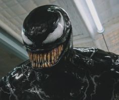 a close up of the face and mouth of a man in a black spider - man suit