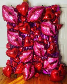 a bunch of heart shaped balloons sitting on top of a wooden floor