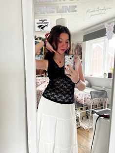 a woman is taking a selfie in the mirror with her cell phone while wearing a black top and white skirt