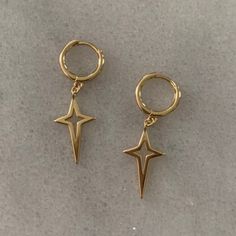 two pairs of gold tone metal earrings with star charms on each earring, one has a hook and the other has a loop