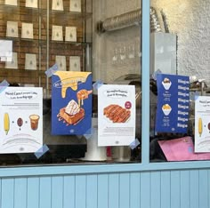 some signs are hanging in the window of a bakery that sells pastries and desserts