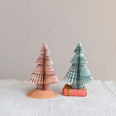 two small trees made out of seashells sitting on top of a white surface