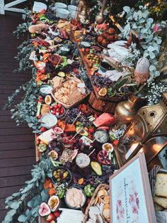 a long table filled with food on top of a wooden floor next to potted plants