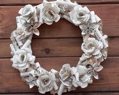 a wreath made out of old book pages with paper flowers on the front and sides