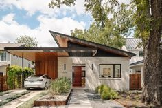 a white car is parked in front of a modern house with wood and stone accents