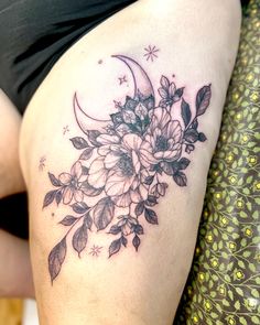 a woman's thigh with flowers and a half moon tattoo on her left side