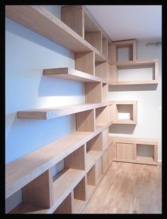 an empty room with wooden shelves on the wall and hard wood flooring in it