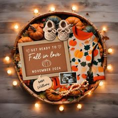 a basket filled with pumpkins and baby shoes next to a sign that says get ready to fall in love