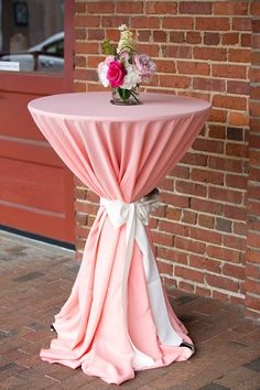 a table with a pink cloth draped over it and some flowers on top of it