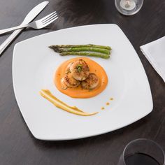 a white plate topped with shrimp and asparagus next to a glass of wine