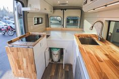 a kitchen area in the back of a truck with wood counter tops and cabinets on both sides