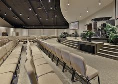 an empty auditorium with rows of seats and plants