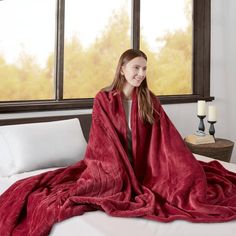 a woman wrapped in a red blanket on top of a bed