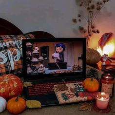 an open laptop computer sitting on top of a table next to candles and pumpkins