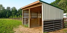 a horse barn with the doors open in a field