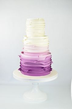 a multi layer cake with purple and white icing