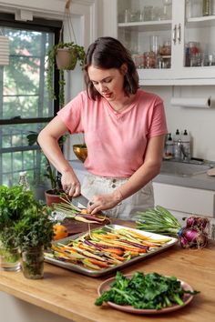 a woman cutting up vegetables on top of a wooden counter