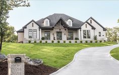 a large white house sitting in the middle of a lush green field next to a driveway