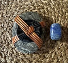 two pieces of wood sitting on top of a woven place mat next to a stone