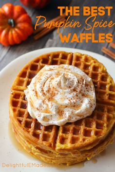 a waffle topped with whipped cream on a white plate next to mini pumpkins