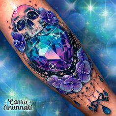 a colorful tattoo with skulls and flowers on the arm, in front of a blue background