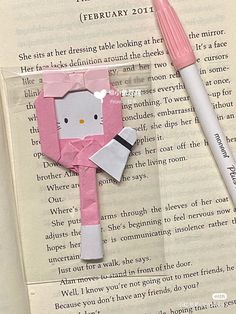 a book with an origami hello kitty on it and a pink pen next to it