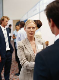 a woman in a business suit is talking to two other people who are looking at her