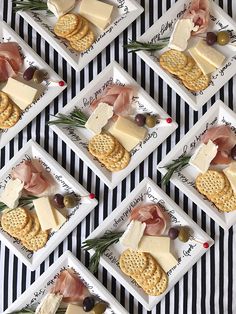 crackers and cheeses are arranged in squares on a black and white striped tablecloth