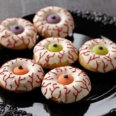 decorated donuts with white icing and red sprinkles on a black plate