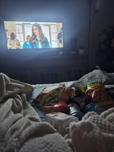 a tv that is on in the dark with food all over it and some snacks