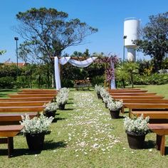 an outdoor ceremony setup with wooden benches and flowers