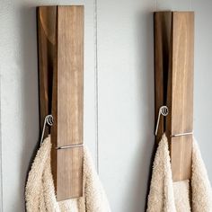 two towels are hanging on the wall in front of each other with wooden hooks attached to them